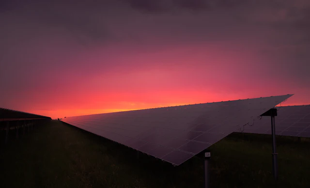 Painel solar contra um céu rosa e alaranjado no fim da tarde