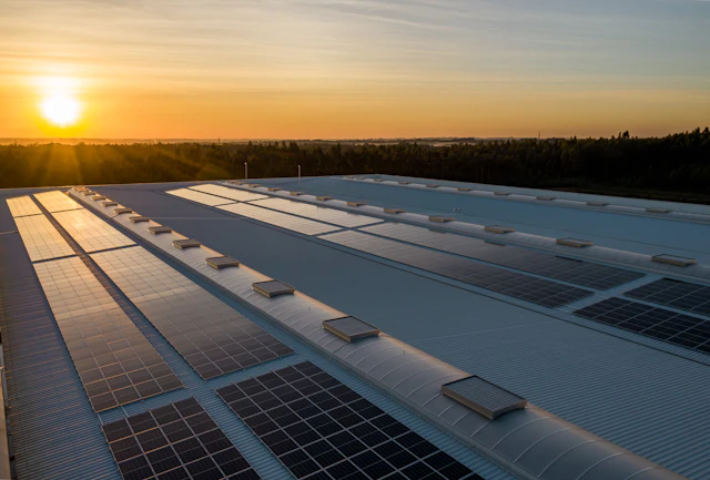 Painéis solares em telhado industrial ao pôr do sol