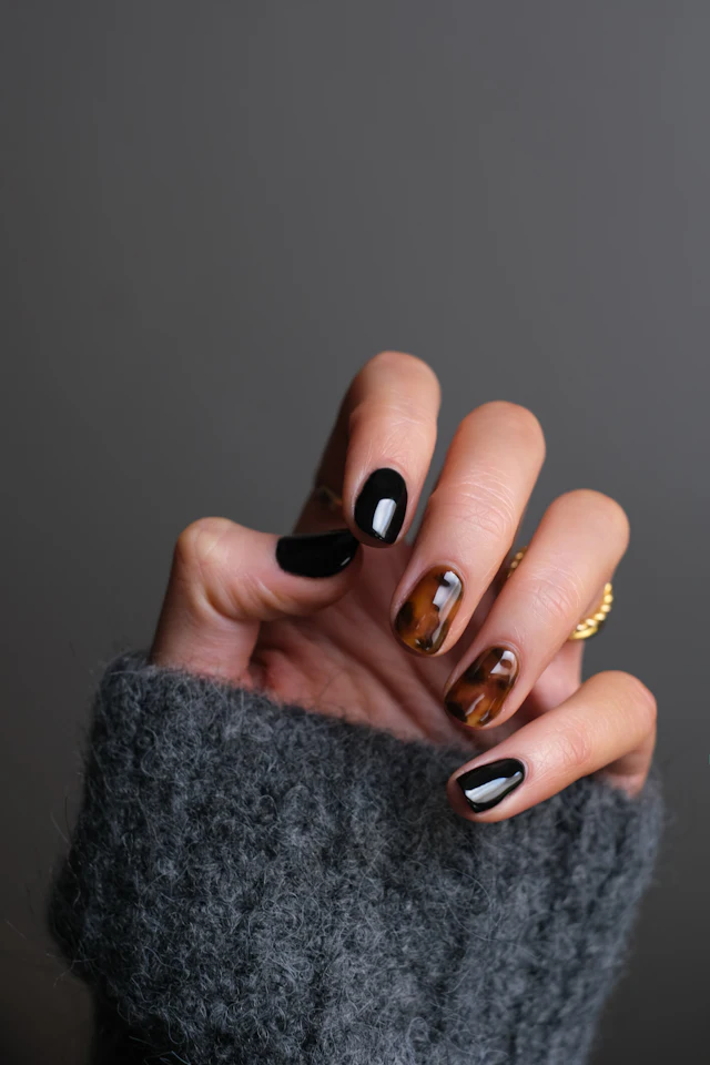 Mão com unhas pretas e detalhes dourados